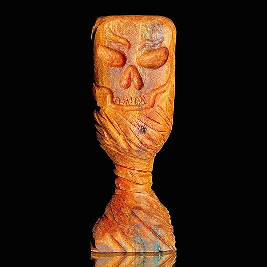 Wooden chalice with a carved skull on a black background.