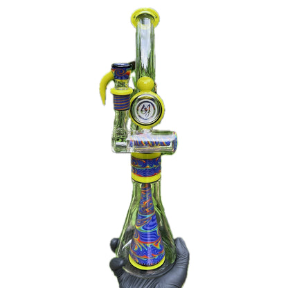 A colorful glass bubbler with a green, blue, and yellow pattern, featuring a matching slide and ash catcher.