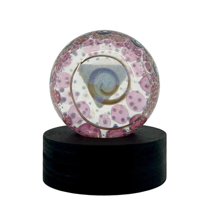 Decorative glass sphere with a colorful pattern on a black stand against a white background