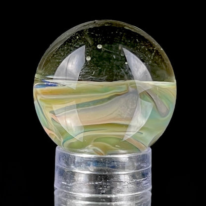 A multicolored glass marble with earth tones, placed on a glass stand.