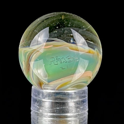 A multicolored glass marble with earth tones, placed on a glass stand.