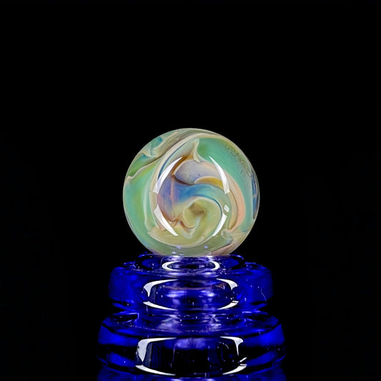A multicolored glass marble with earth tones, placed on a blue stand, against a black background.