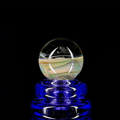 A multicolored glass marble with earth tones, placed on a blue glass stand.