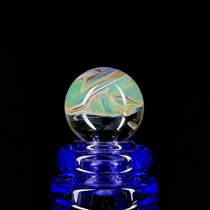 A multicolored glass marble with earth tones, placed on a blue glass stand.