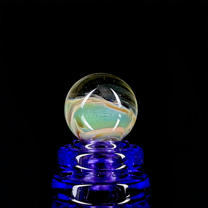 A multicolored glass marble with earth tones, placed on a blue glass stand.