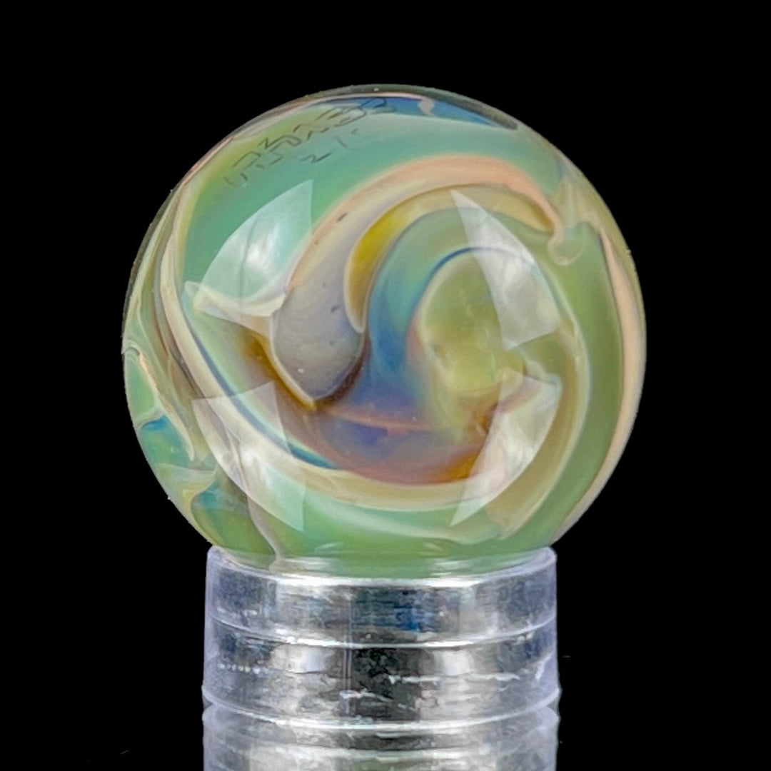 A multicolored glass marble with earth tones, placed on a glass stand.