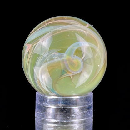 A multicolored glass marble with earth tones, placed on a glass stand.