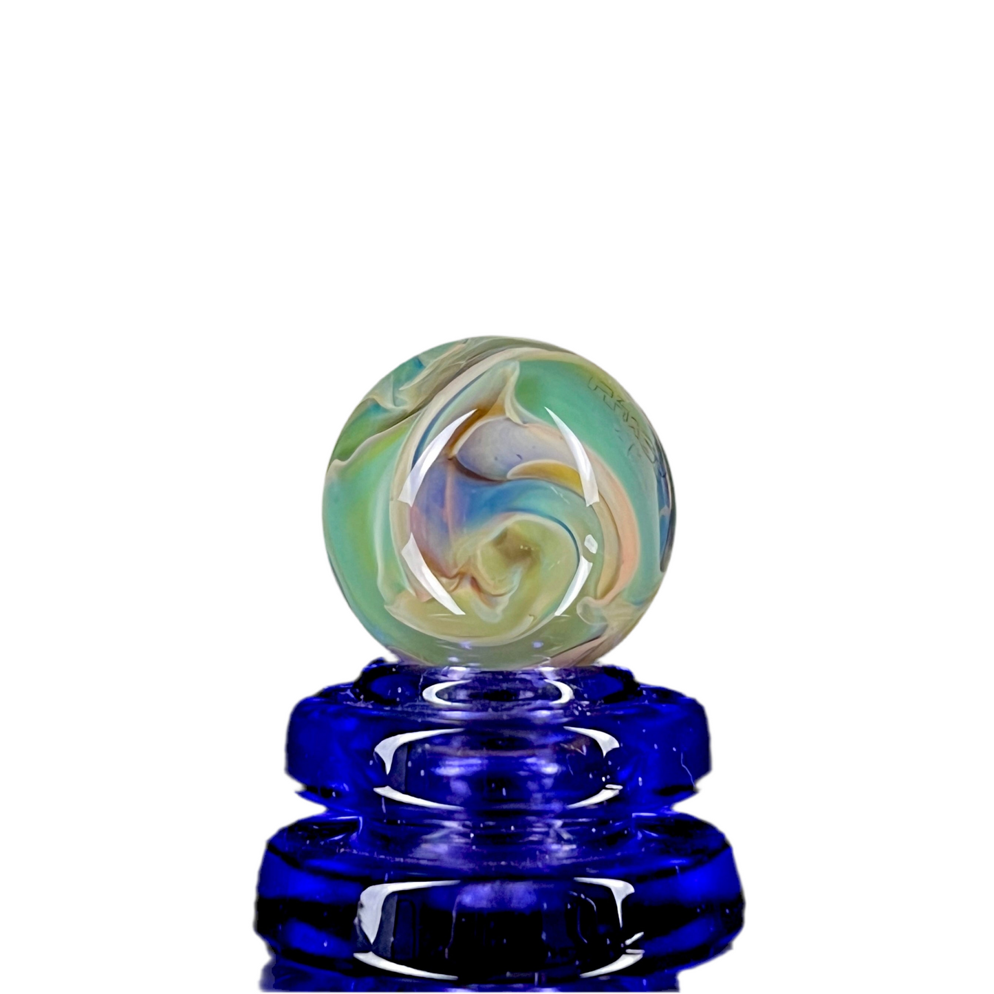 A multicolored glass marble with earth tones, placed on a blue glass stand.