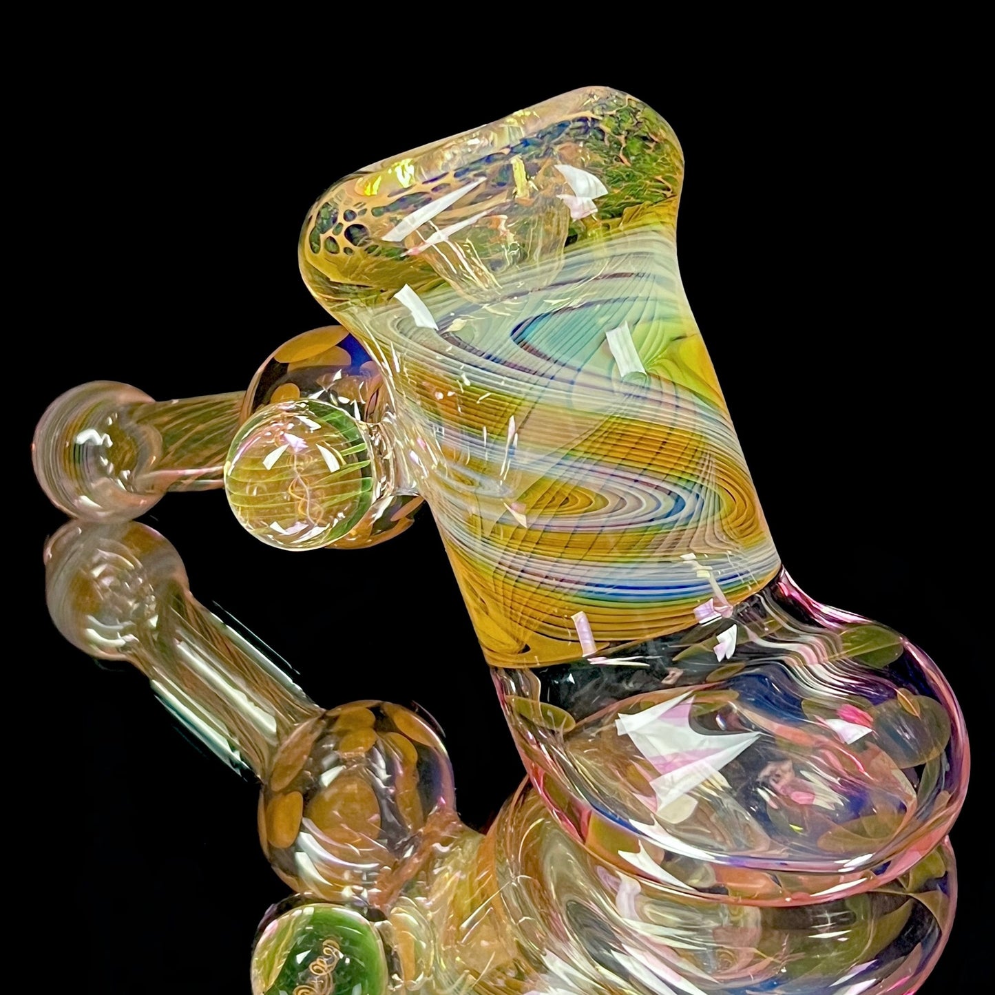 A colorful glass hammer-shaped piece with gold and silver fume patterns.