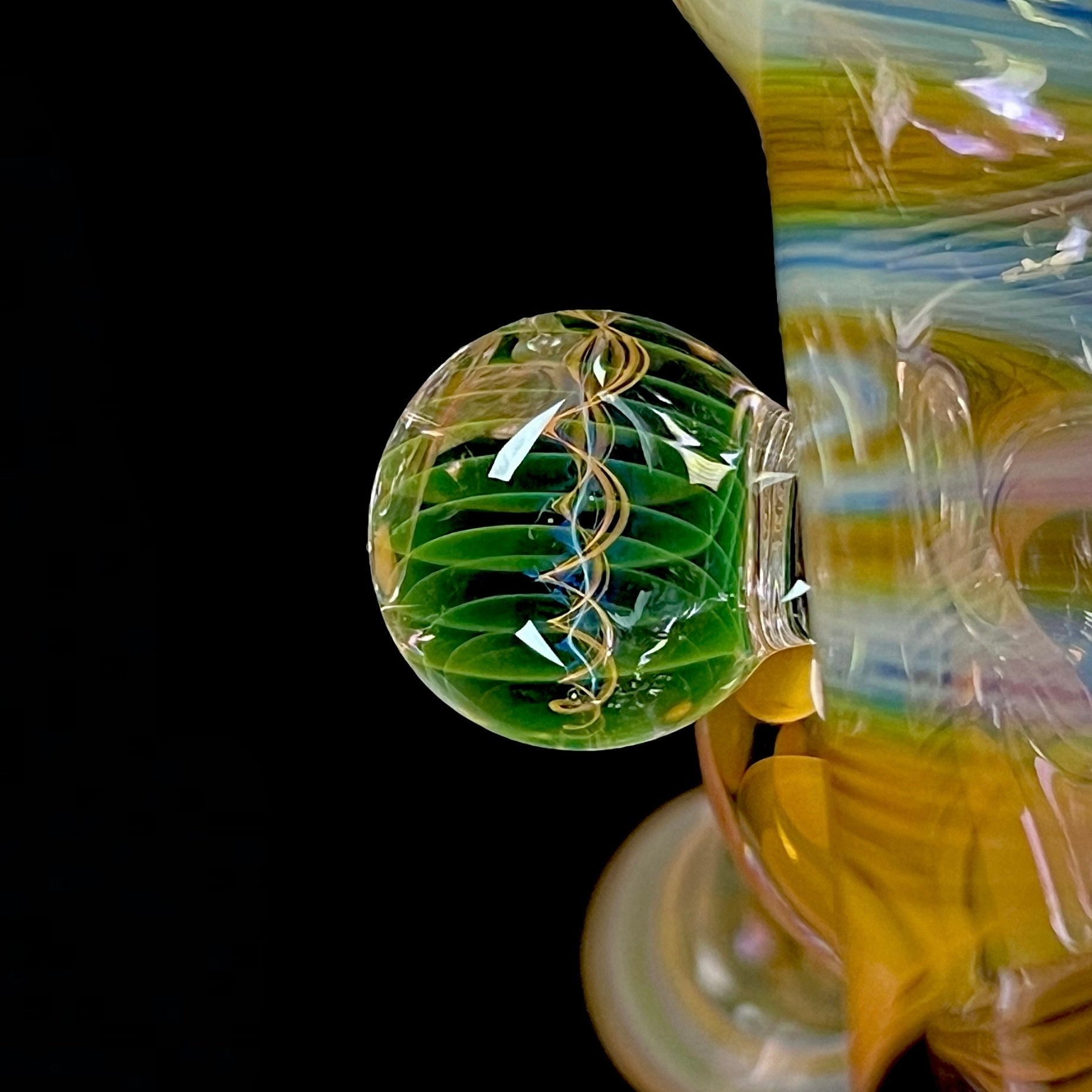 A close up of a multicolored glass hammer-style pipe with intricate patterns and a round bowl.