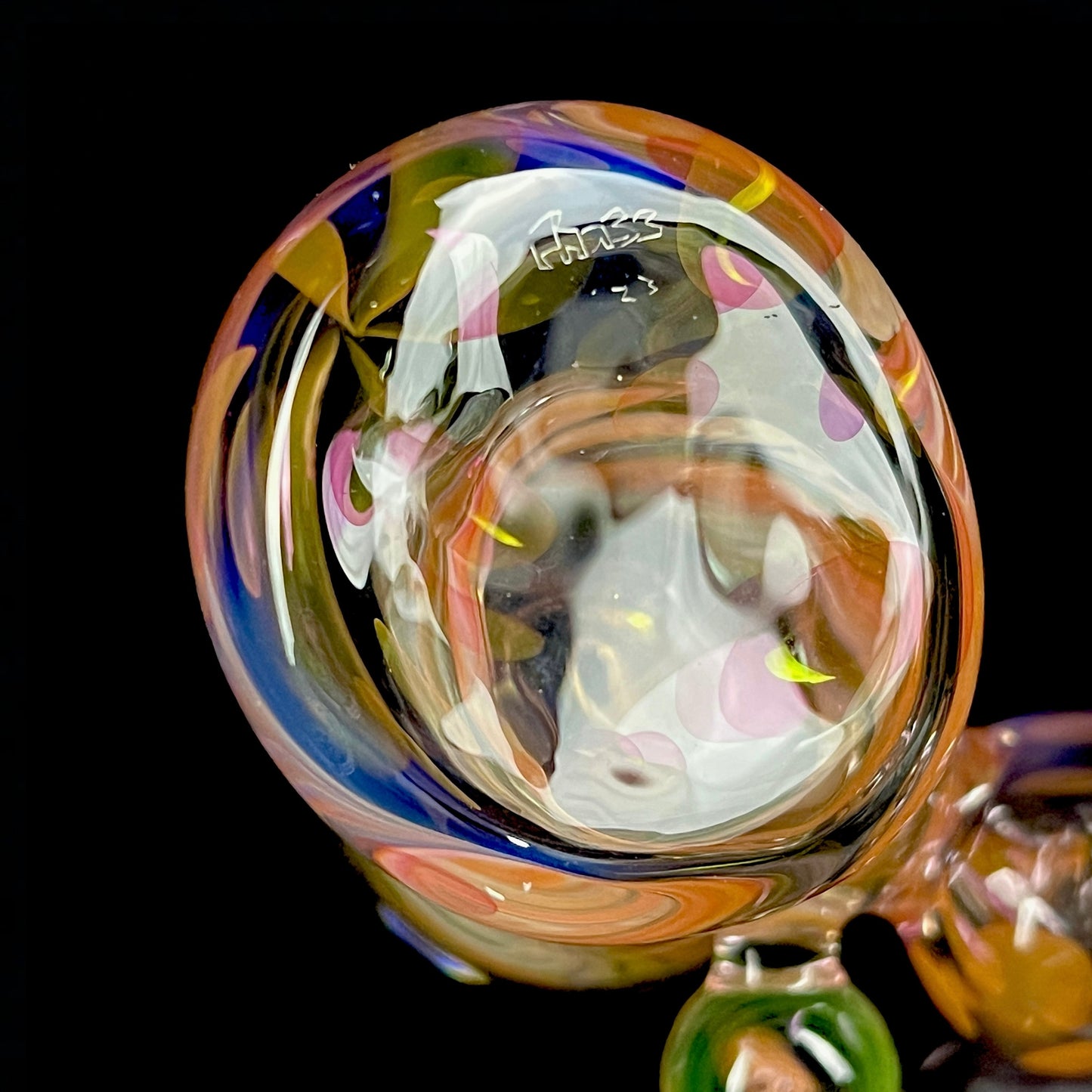 A close up of a multicolored glass hammer-style pipe with intricate patterns and a round bowl.