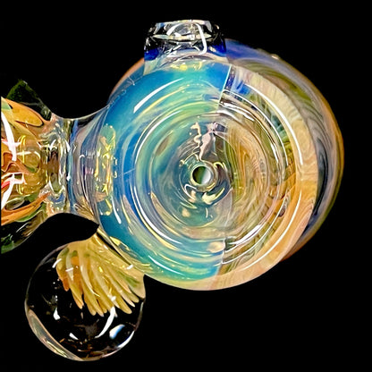 A colorful glass hammer-shaped piece with blue, gold, and silver fume patterns.