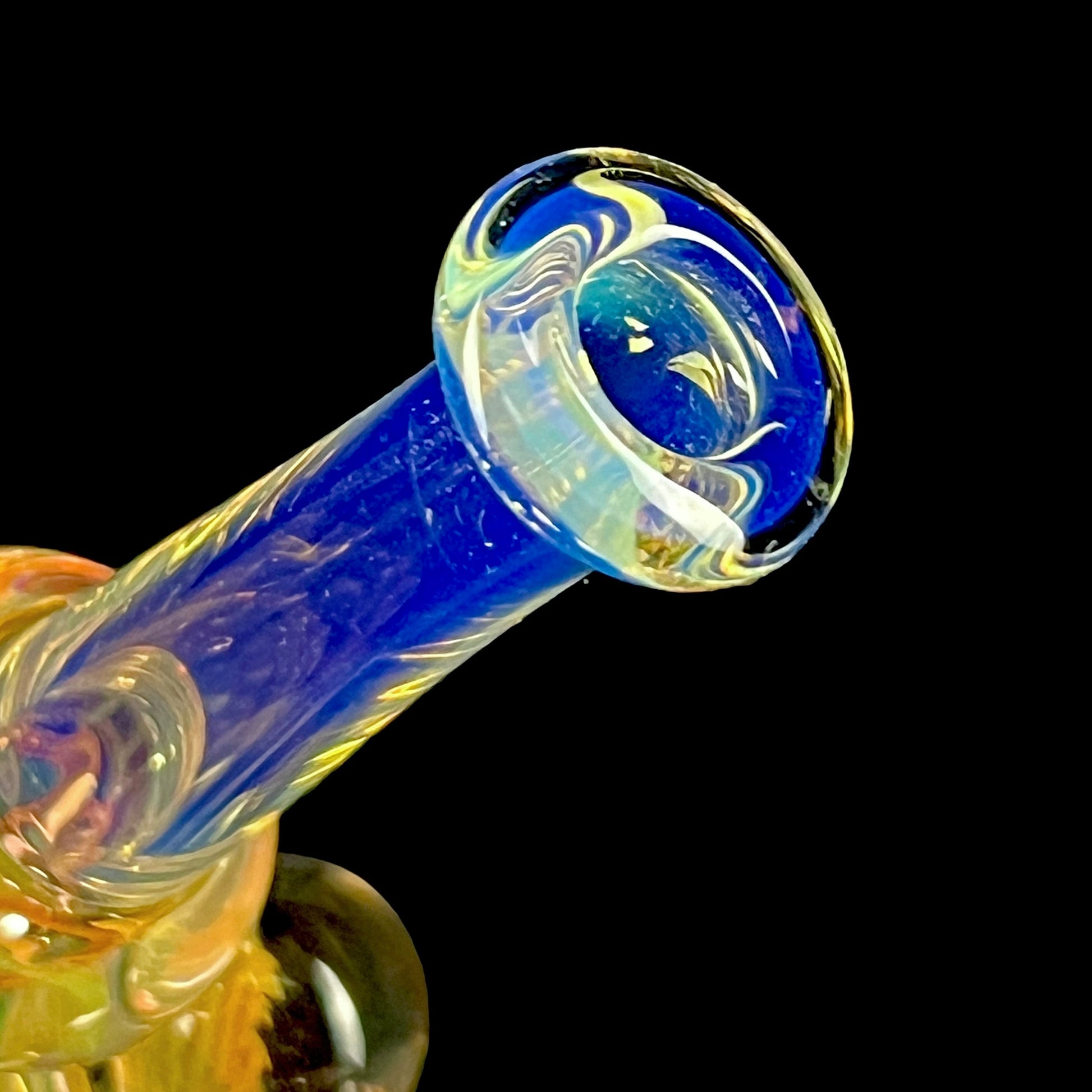 A colorful glass hammer-shaped piece with blue, gold, and silver fume patterns.