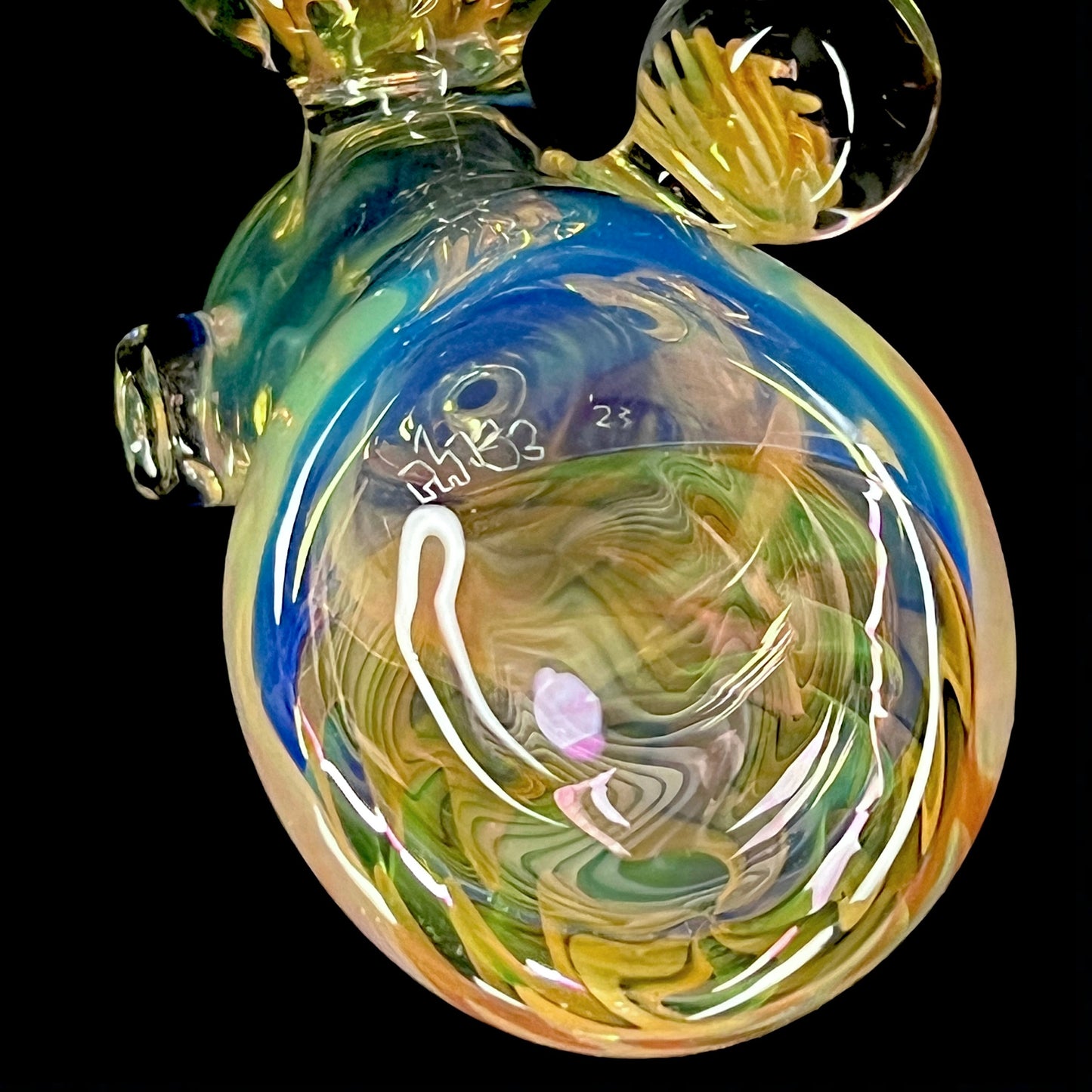 A colorful glass hammer-shaped piece with blue, gold, and silver fume patterns.