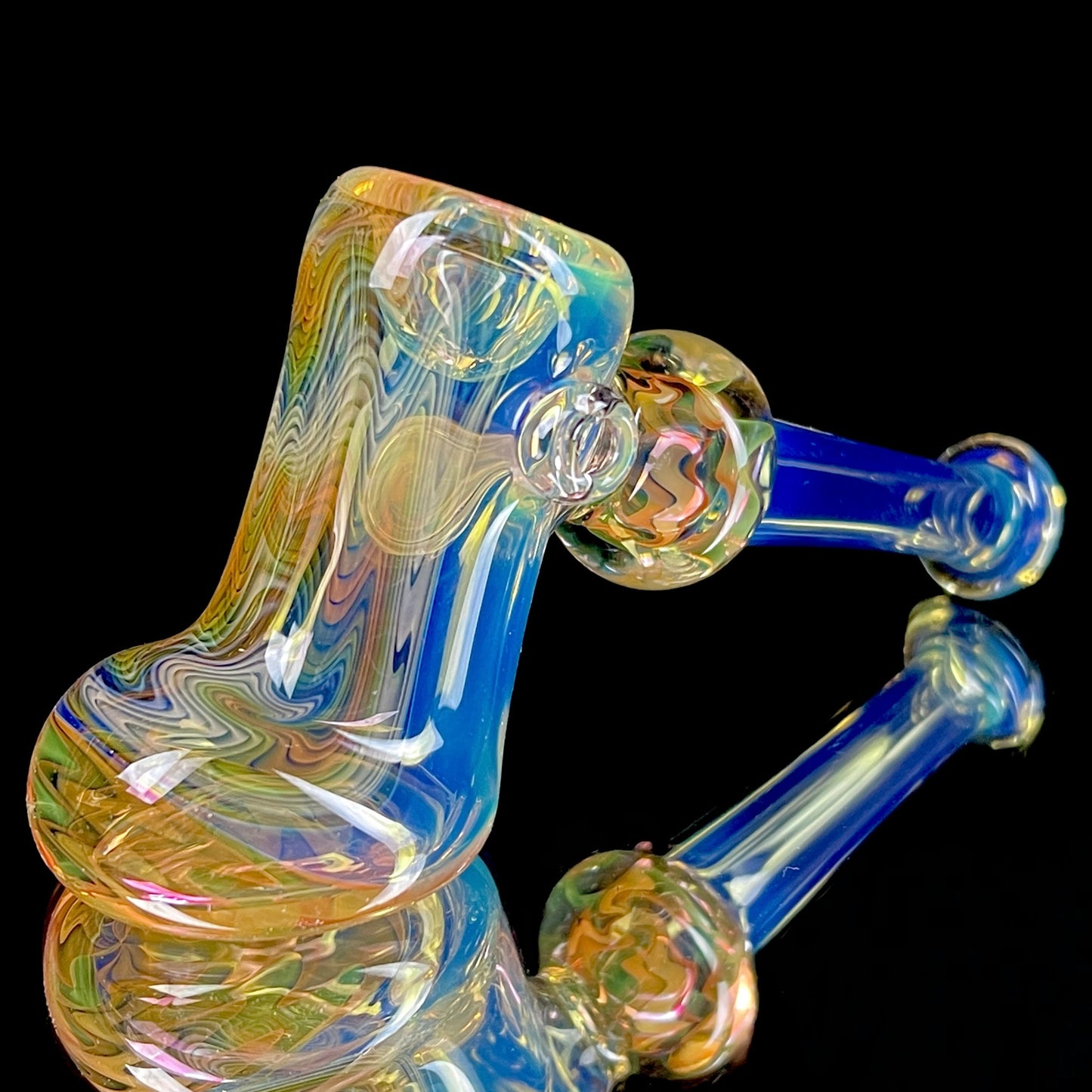 A colorful glass hammer-shaped piece with blue, gold, and silver fume patterns.