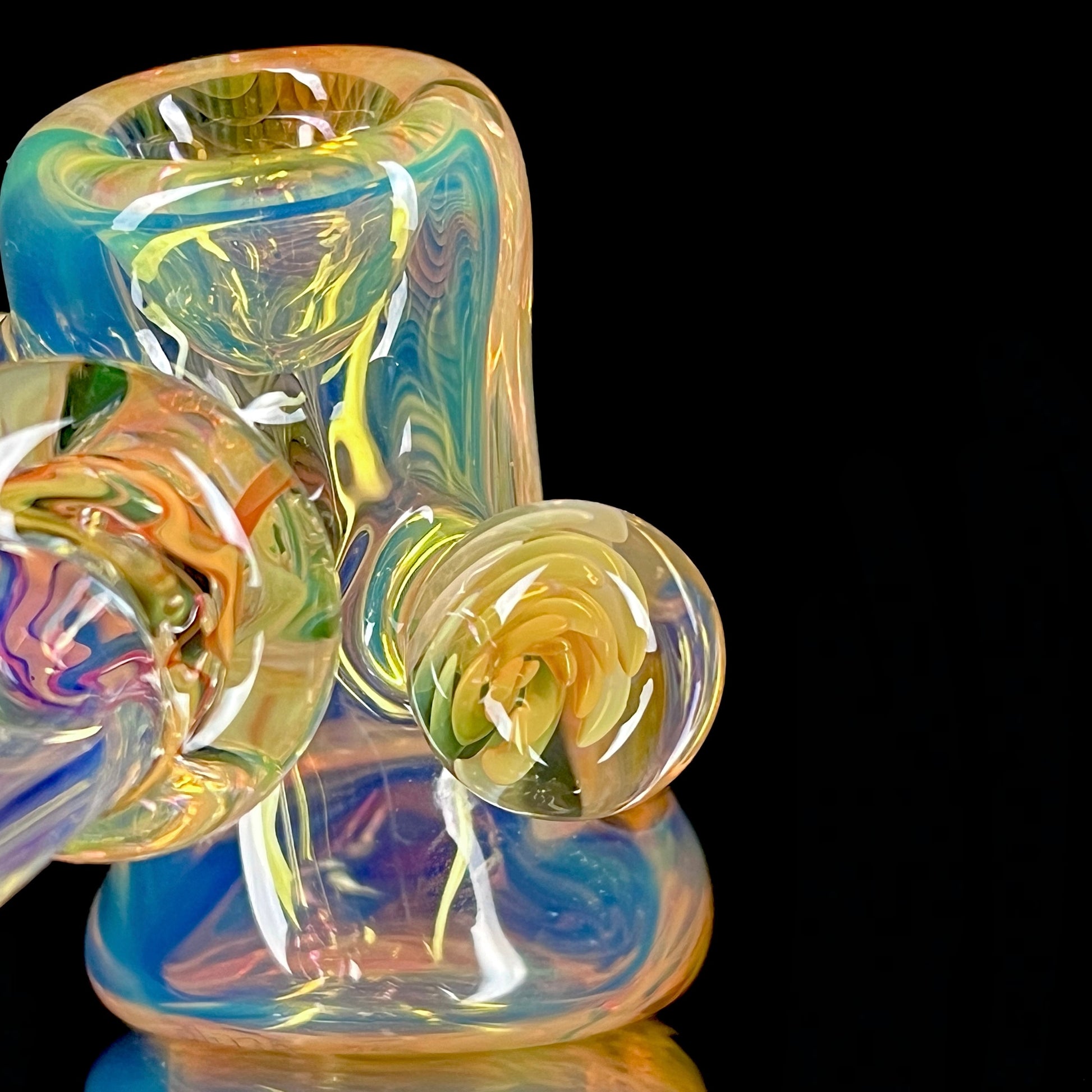A colorful glass hammer-shaped piece with blue, gold, and silver fume patterns.