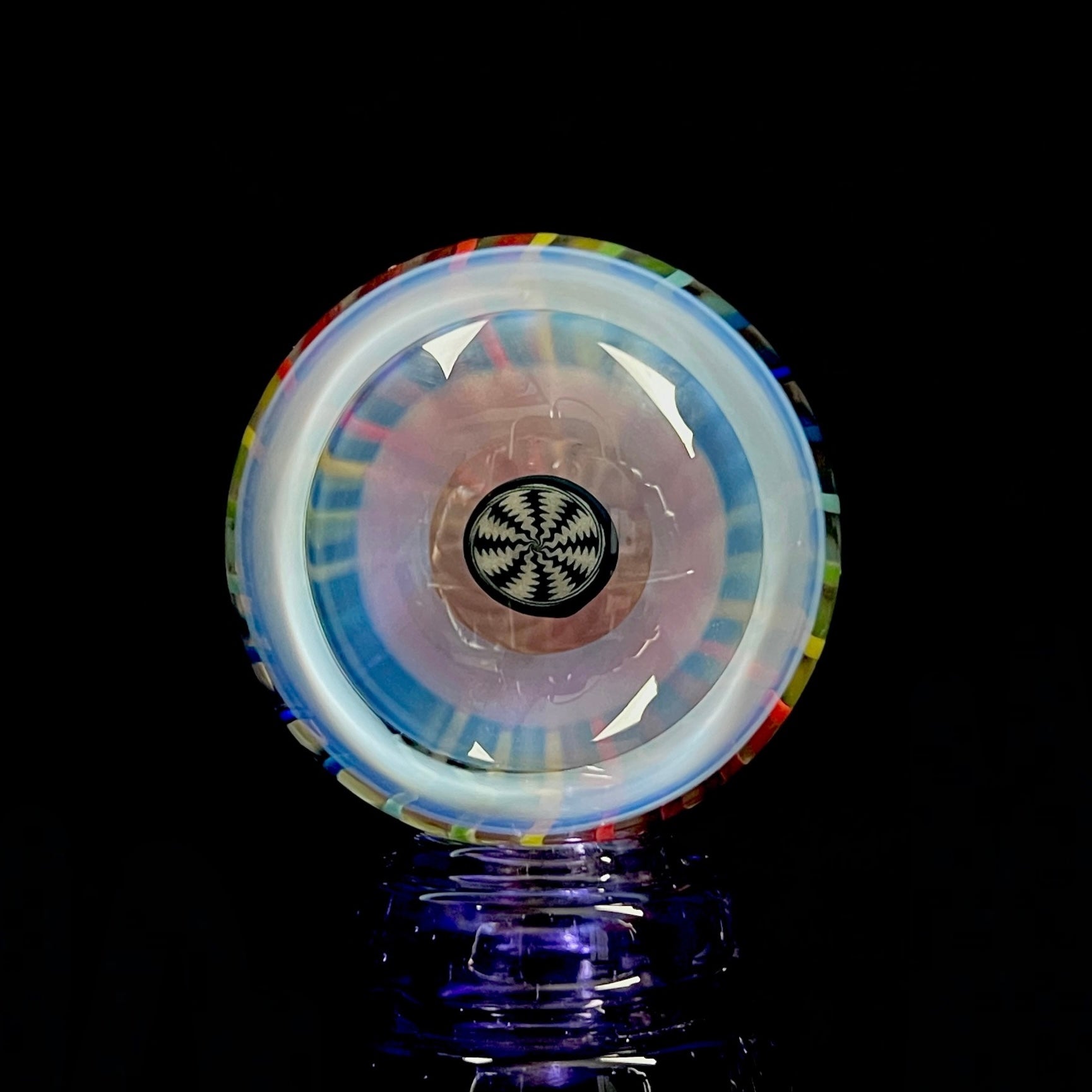 A multicolored glass marble, resembling a pinwheel, with a central hub and outer rim.