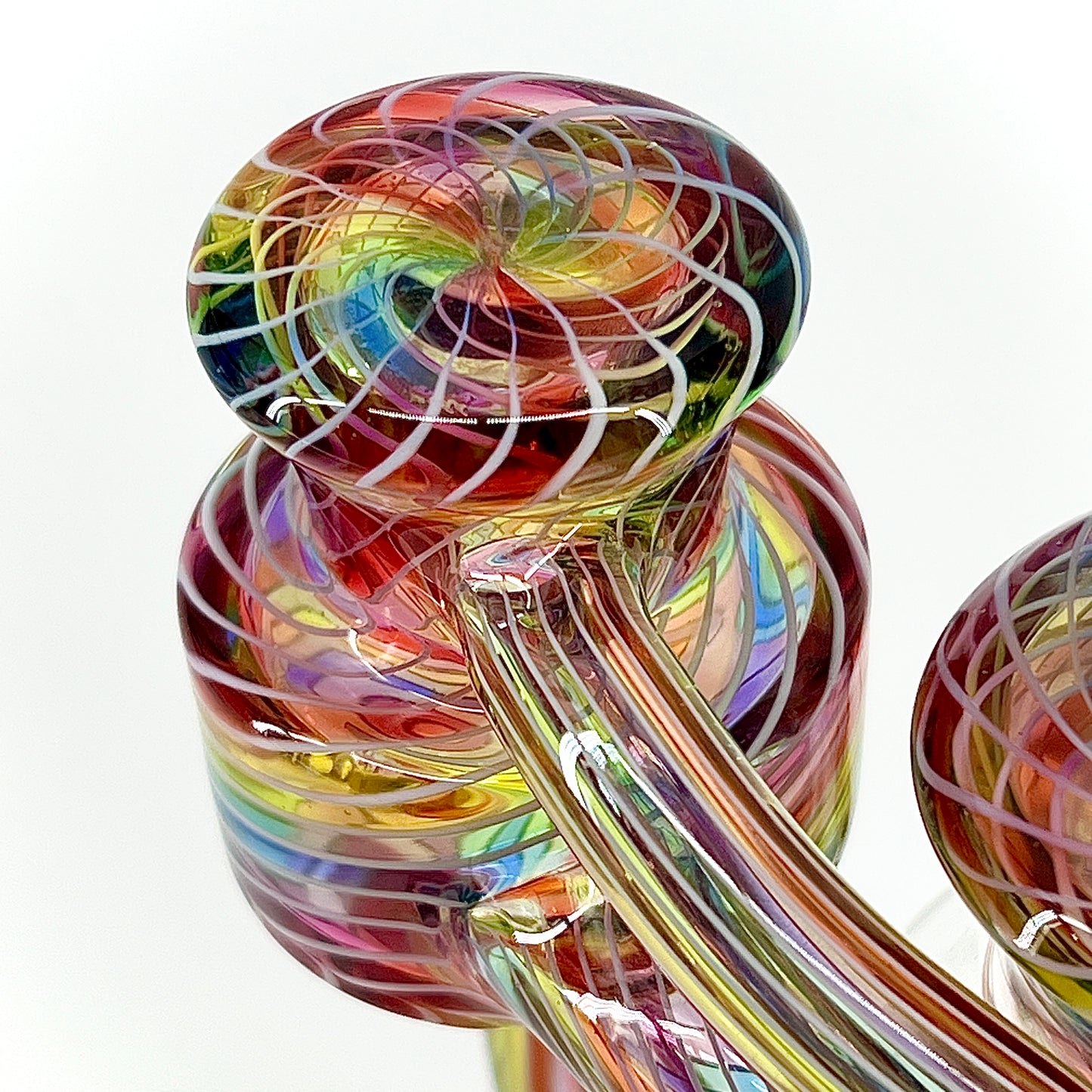 Multicolored glass sculpture with swirling patterns on a white background.