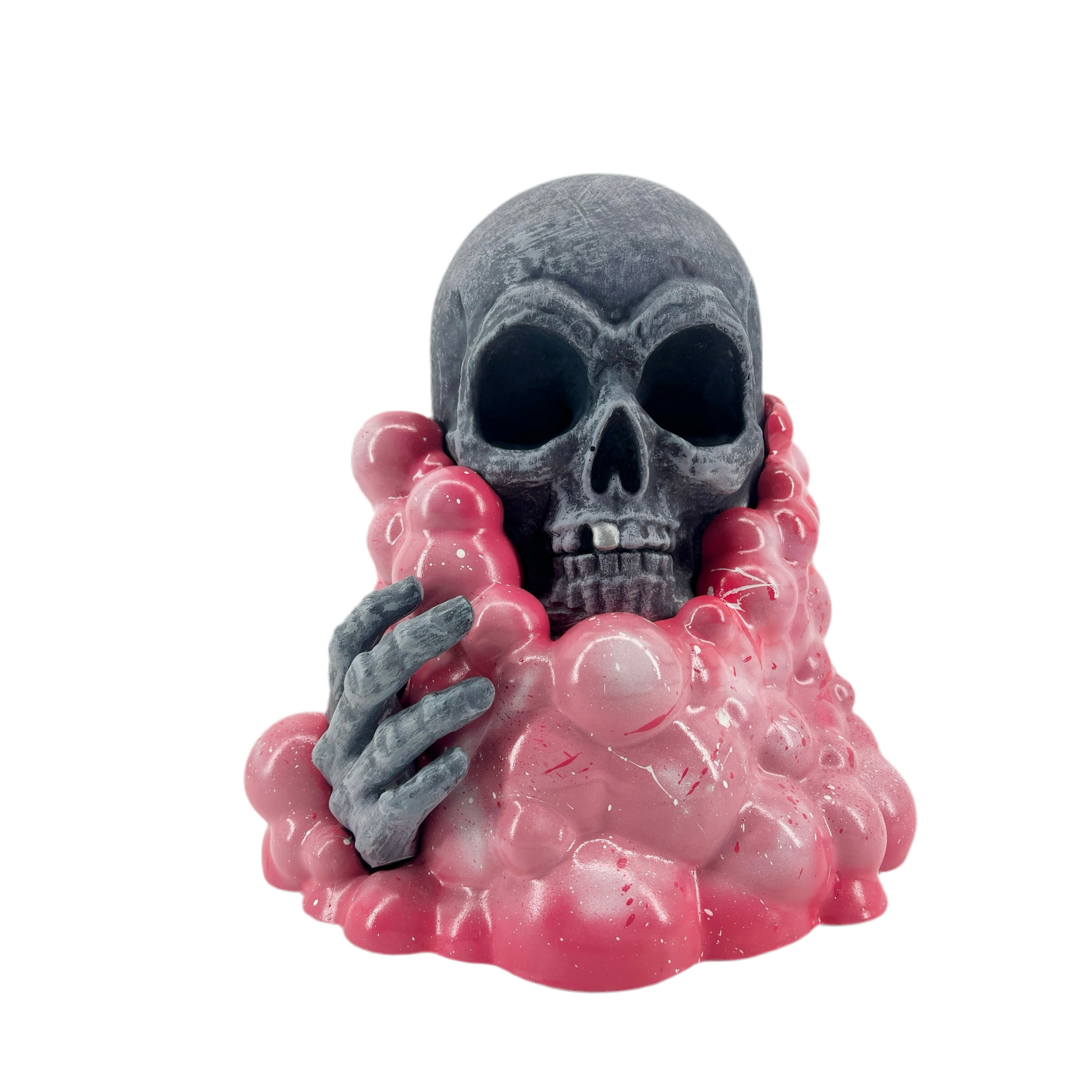 Skull figurine with pink base and gray hand on a white background.