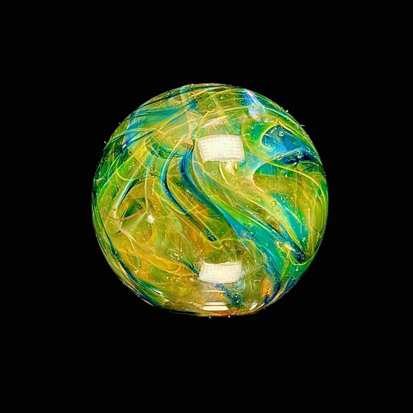 Colorful glass marble with swirling patterns on a black background