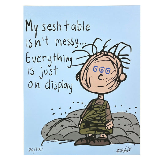 A framed print featuring a cartoon character with the caption 'My sesh table isn't messy... Everything is just on display'.