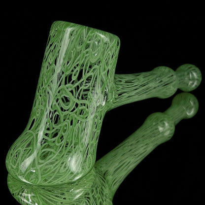 A jade green glass hand pipe with intricate patterns.