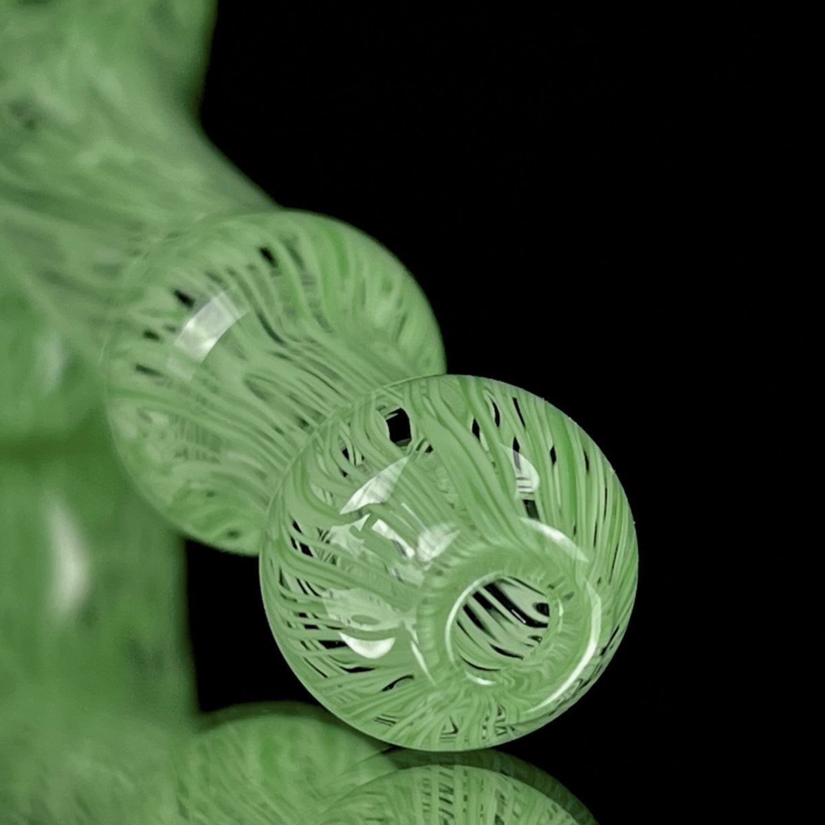 A jade green glass hand pipe with intricate patterns.