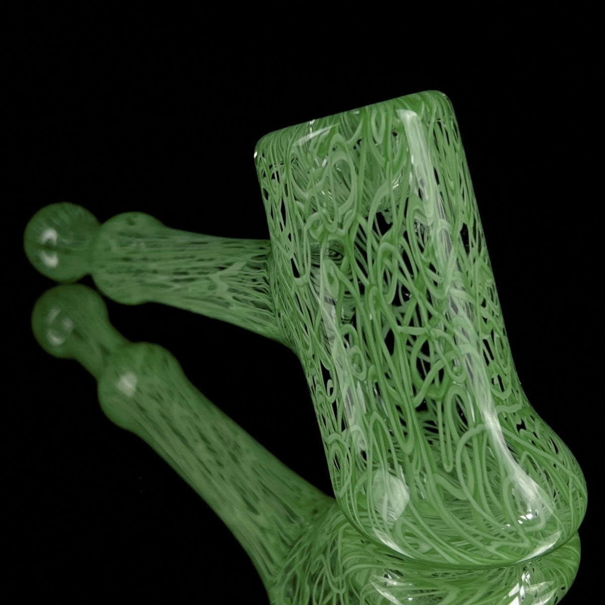 A jade green glass hand pipe with intricate patterns.
