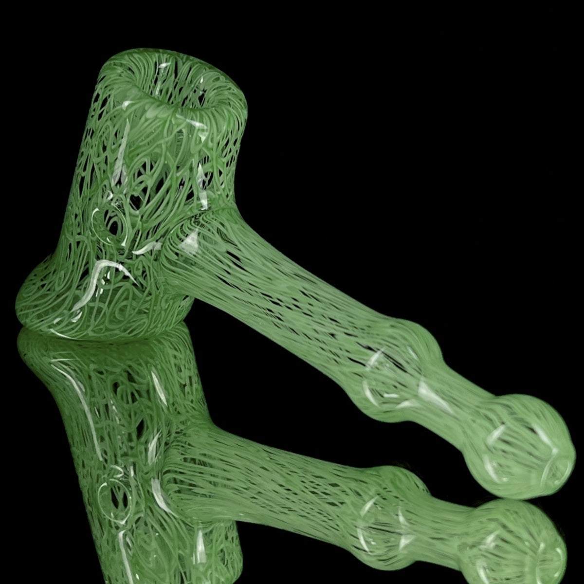 A jade green glass hand pipe with intricate patterns.