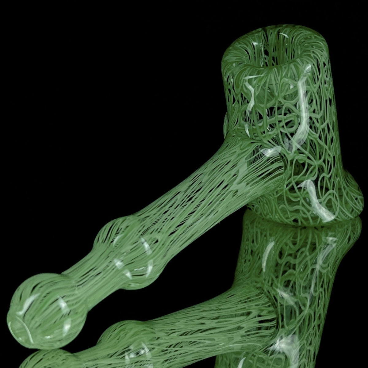 A jade green glass hand pipe with intricate patterns.