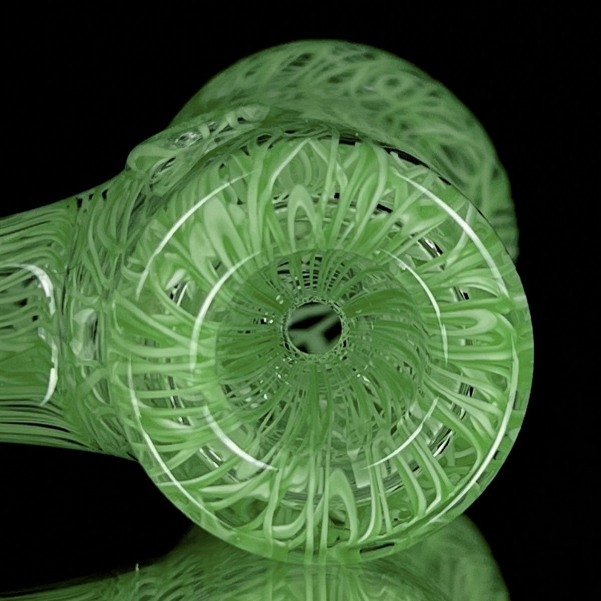 A jade green glass hand pipe with intricate patterns.