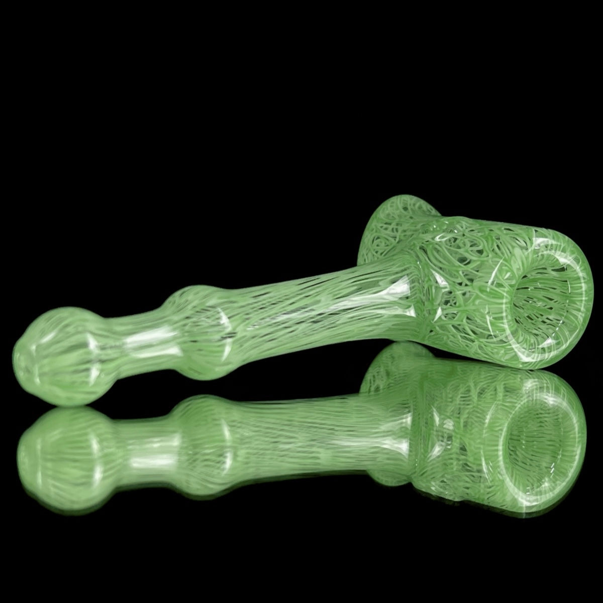 A jade green glass hand pipe with intricate patterns.