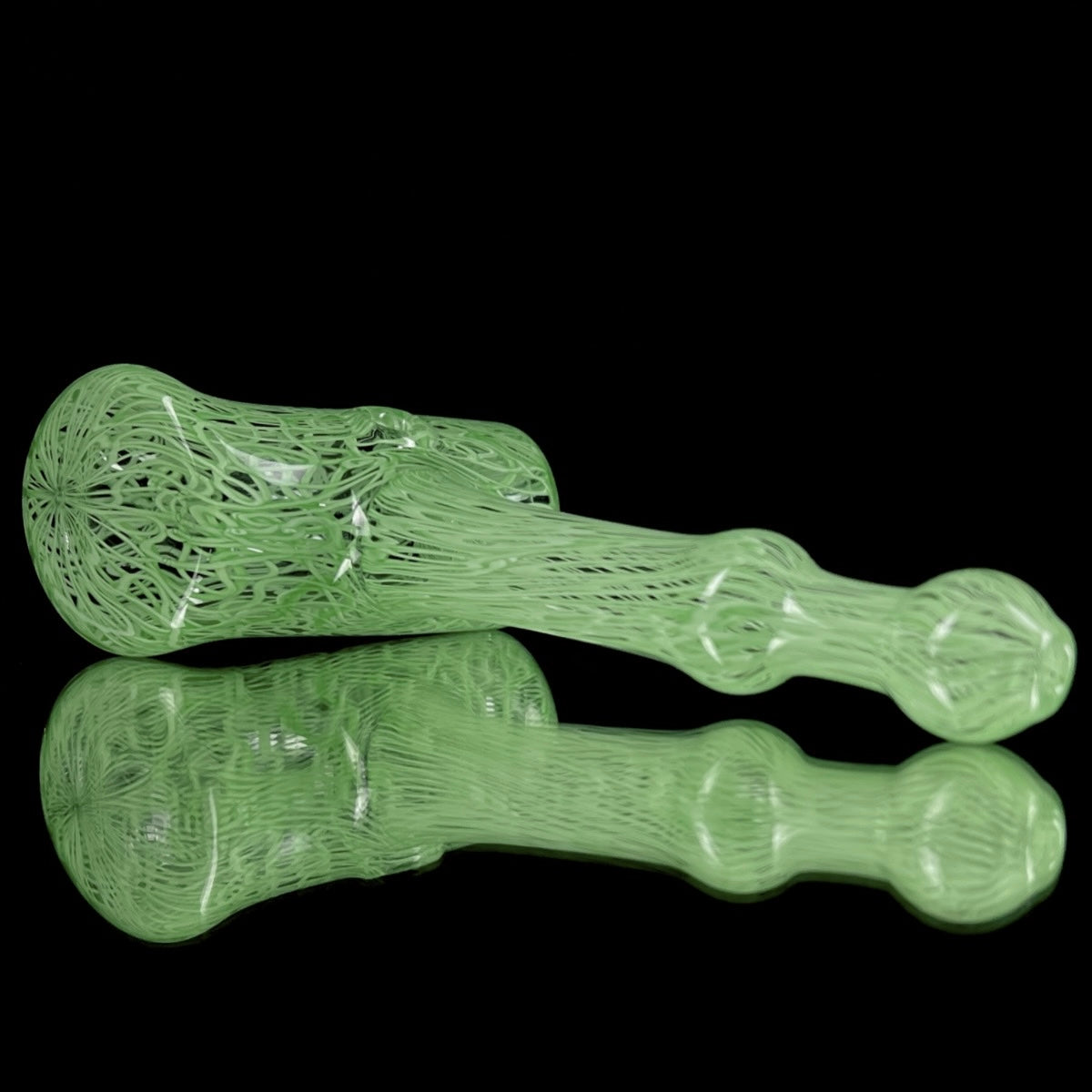 A jade green glass hand pipe with intricate patterns.