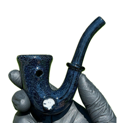 A hand holding a purple glass Sherlock pipe with a character illustration on the bowl.
