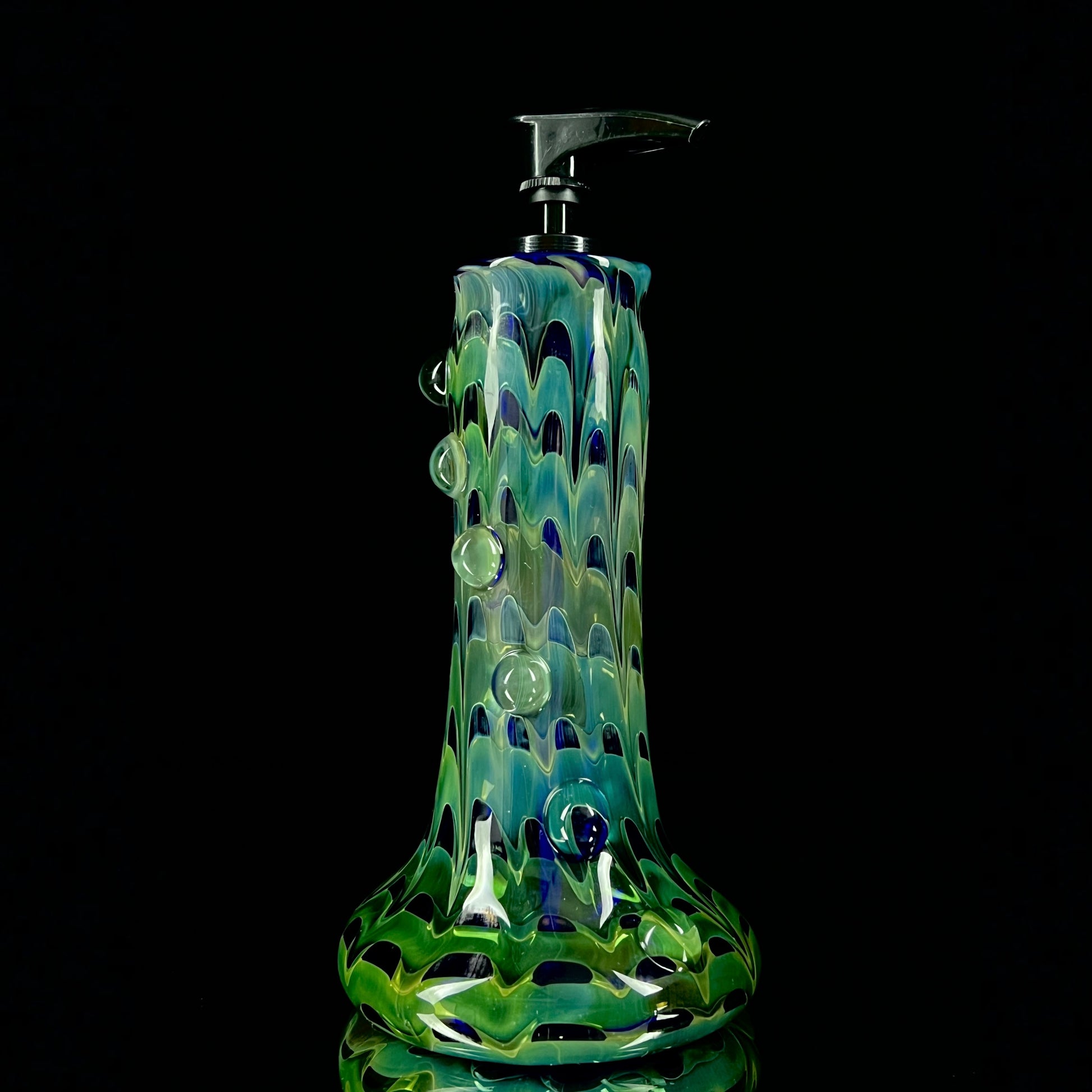 A cobalt blue and green glass soap dispenser with a swirling pattern design.