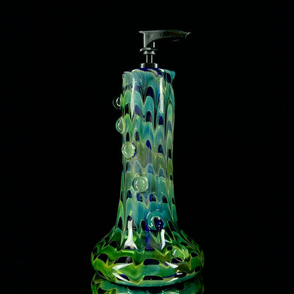 A cobalt blue and green glass soap dispenser with a swirling pattern design.