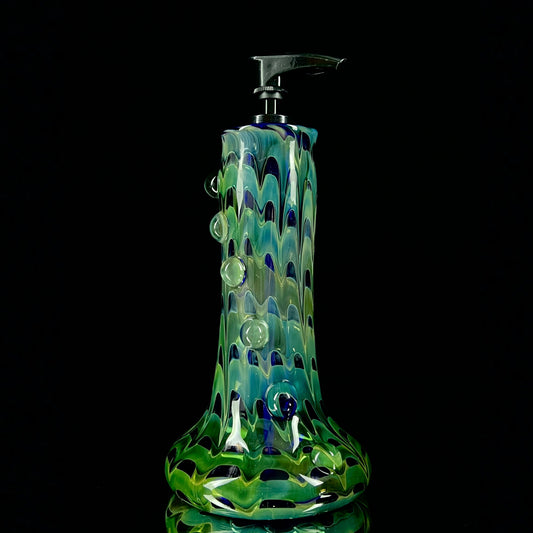 A cobalt blue and green glass soap dispenser with a swirling pattern design.