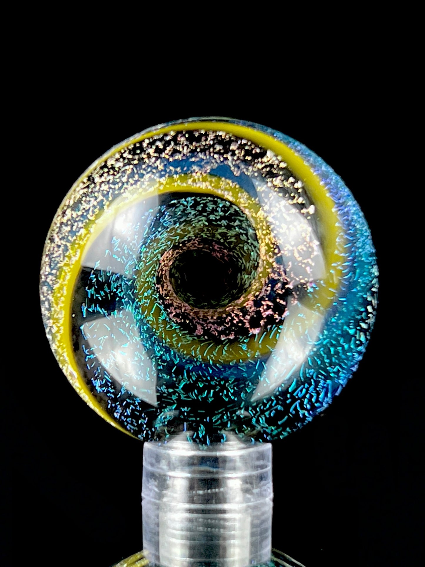 A multicolored glass marble with a visible swirling pattern, predominantly in blue and yellow hues, against a black background.
