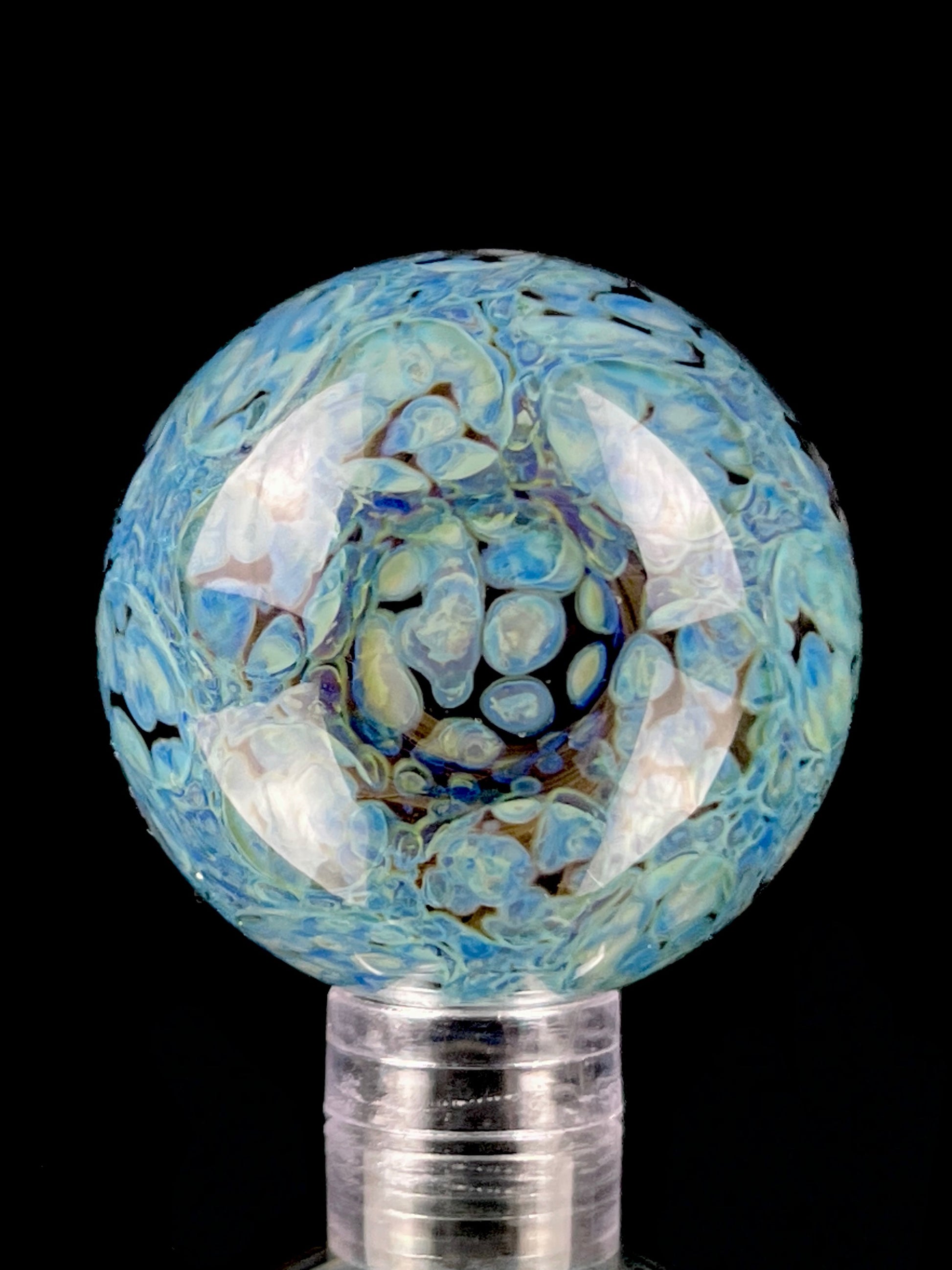 A multicolored glass marble against a black background.