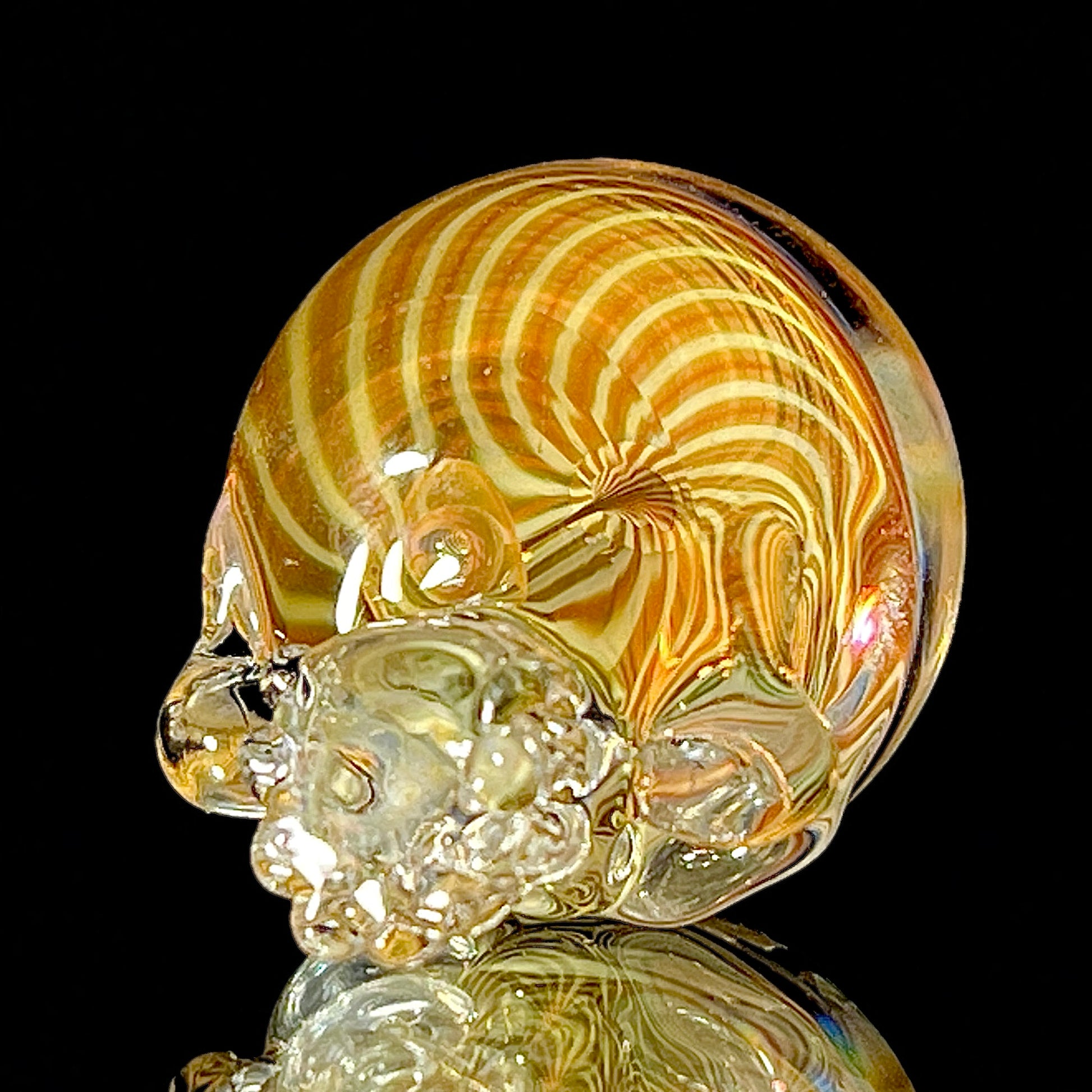 Decorative glass sculpture of a skull with swirling patterns on a black background