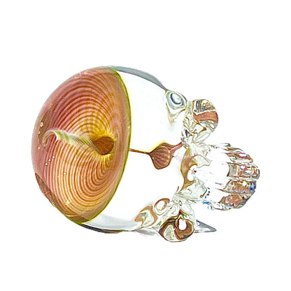 Decorative glass skull with a pink and gold spiral-like design on a white background