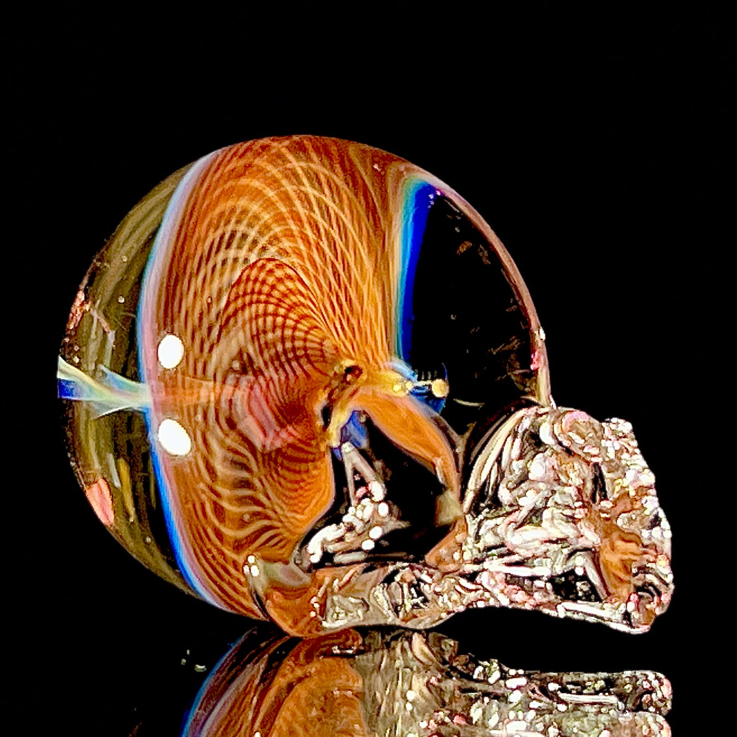 Glass skull sculpture with multicolored patterns on a black background