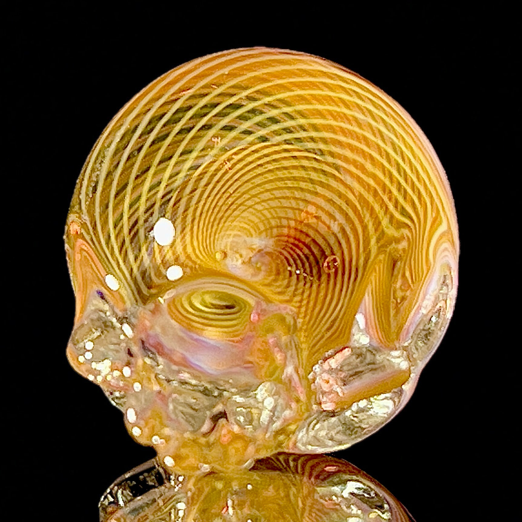 Close-up of a glass skull with concentric patterns on a black background