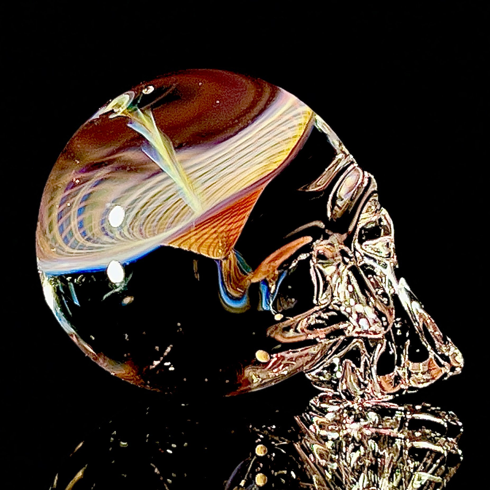 Glass skull sculpture with multicolored swirls against a black background