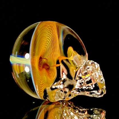 Glass skull paperweight with multicolored swirls on a black background