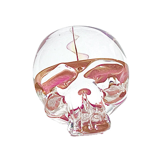 Clear glass skull paperweight with pink and orange interior on a white background.