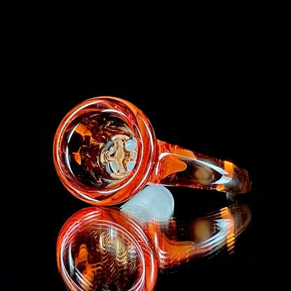 A glass slide with a curved orange bowl attached to a white stem.