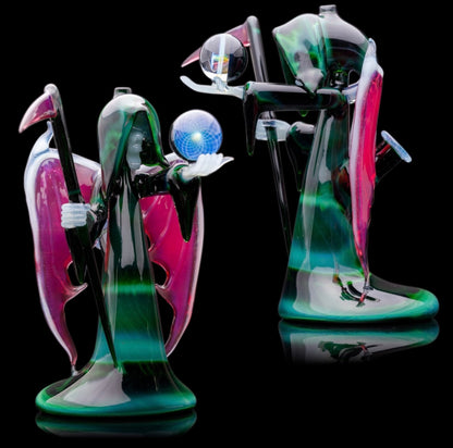 A custom glass piece by Joachim Dallant featuring a winged reaper figure with a colorful backdrop, incorporating a Fumicello orb and a removable scythe dabber.