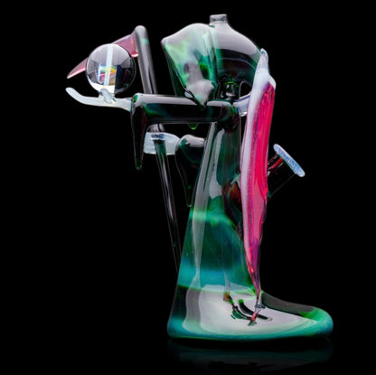 A custom glass piece by Joachim Dallant featuring a winged reaper figure with a colorful backdrop, incorporating a Fumicello orb and a removable scythe dabber.