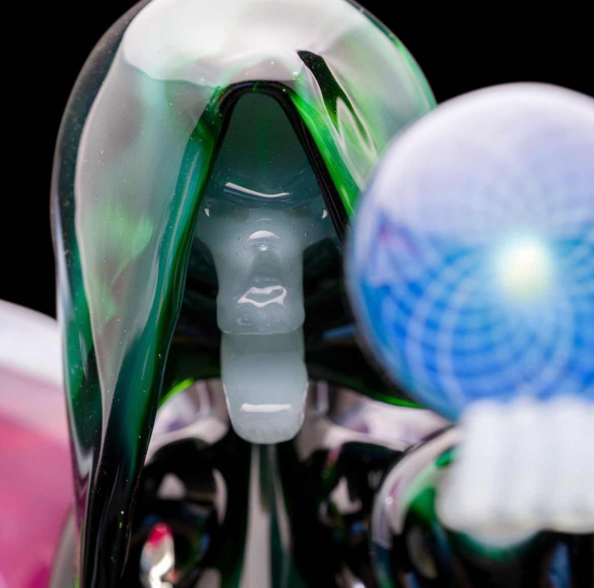 A custom glass piece by Joachim Dallant featuring a winged reaper figure with a colorful backdrop, incorporating a Fumicello orb and a removable scythe dabber.